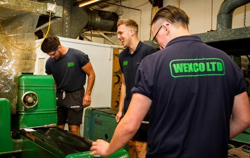 3 males working on green machinery and wearing 'Wexco Ltd' tshirts.