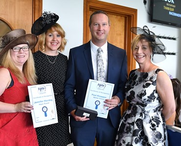 4 adults dressed smartly and smiling whilst holding travel agency awards