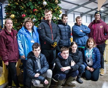 Group of students stood in front of a Christmas tree at a farm.