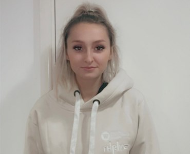 Portrait photo of female student wearing a Thrive student hoodie.