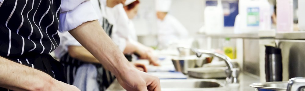 A close up of a group of student chefs working in a hospitality kitchen