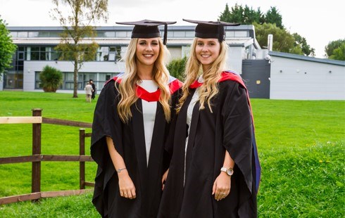 Two female students in graduation cap and gowns