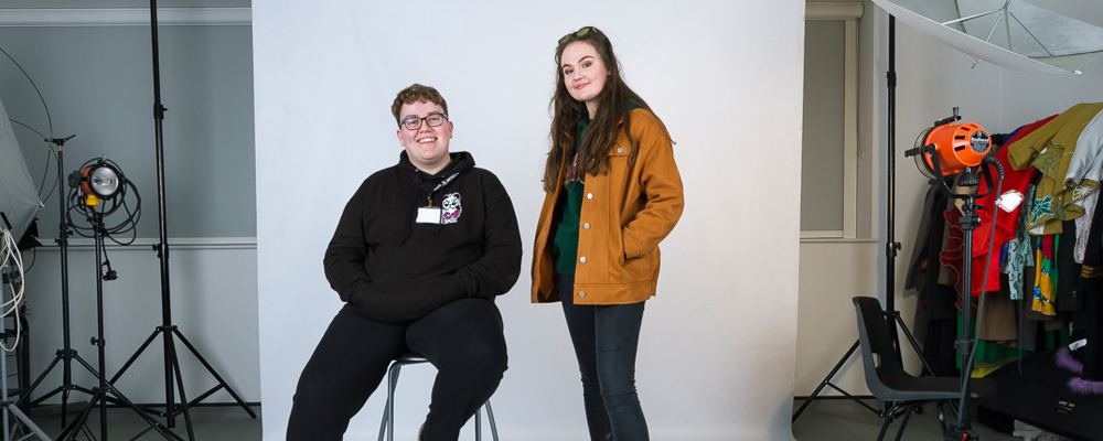 Male and female student smiling in a photography studio