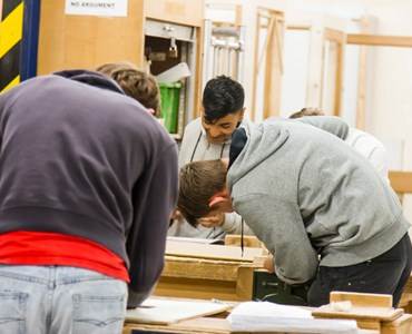 Group of students working at wooden benches.