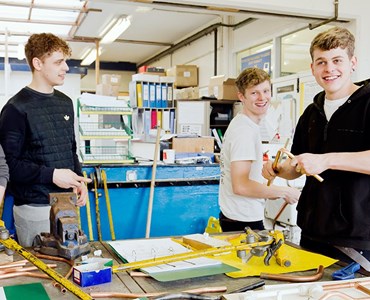 Group of male students working around a desk and laughing