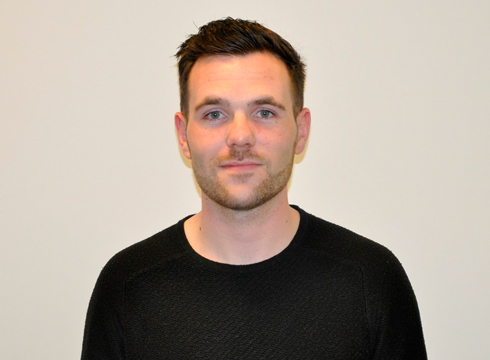 Close up photo of male in black tshirt in front of a white background