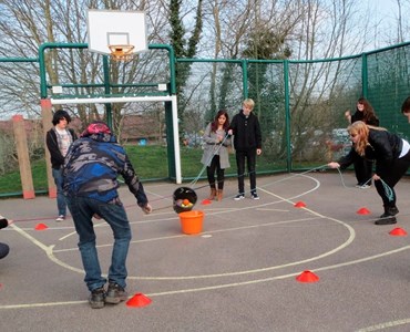 Group of students in an outdoor sports court completing team building tasks.
