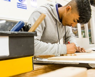 male student holding pencil and working in text book.