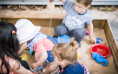 Four nursery children playing in sandpit at HoW College nursery