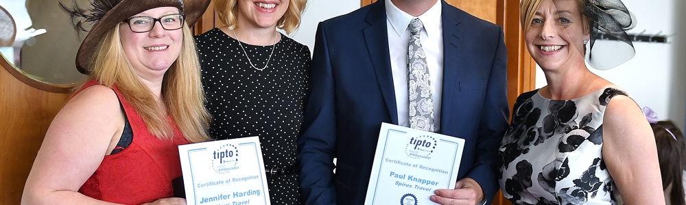 4 adults dressed smartly and smiling whilst holding travel agency awards