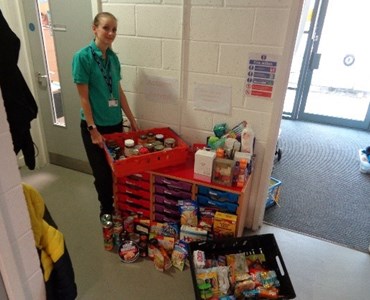 Female standing next to shelves and boxes full of food donations