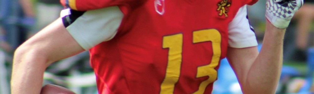 Male American football player running in red uniform whilst holding the ball