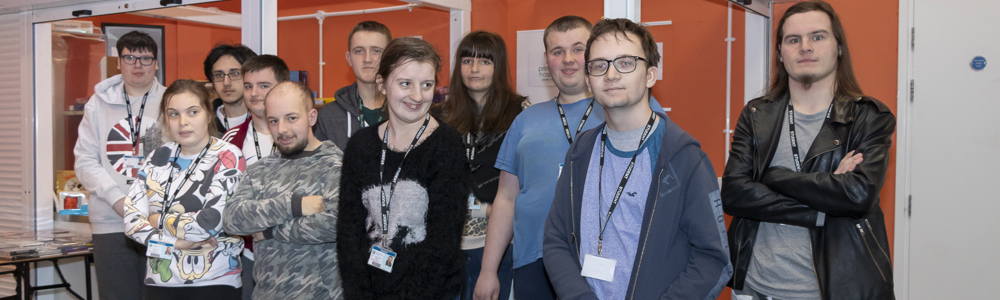 Large group of students smiling in front of an orange wall