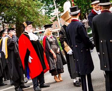 A large graduation procession in robes lined up outside
