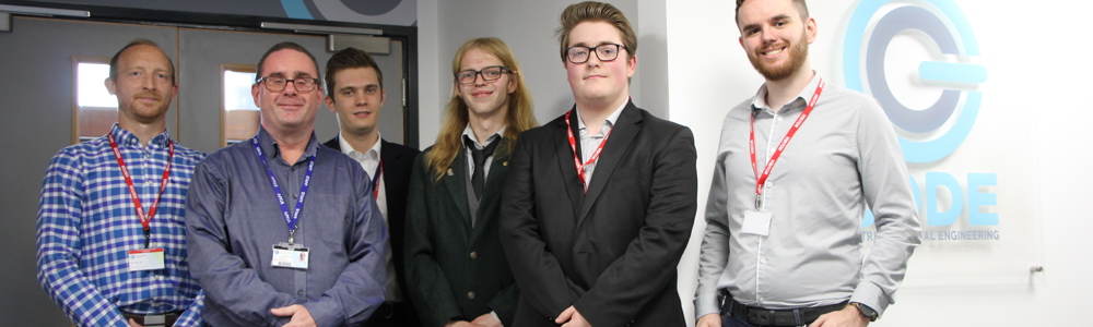 Six smartly dressed males stood in front of college department logo that reads: CODE (Centre of Digital Engineering)