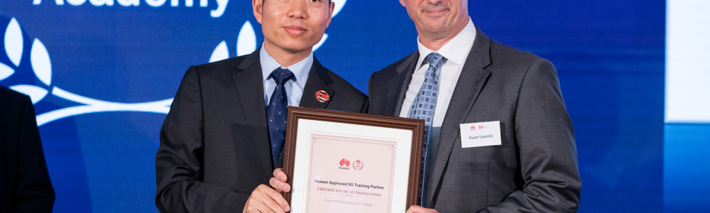 Two smartly dressed males holding a framed certificate at an awards ceremony.