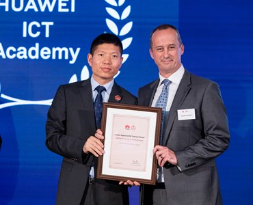 Two smartly dressed males holding a framed certificate at an awards ceremony.