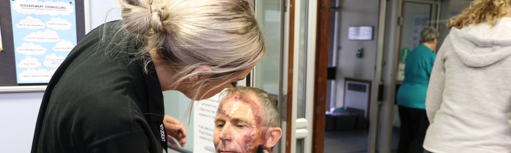 Beauty therapy student doing media makeup on the face of an adult male.