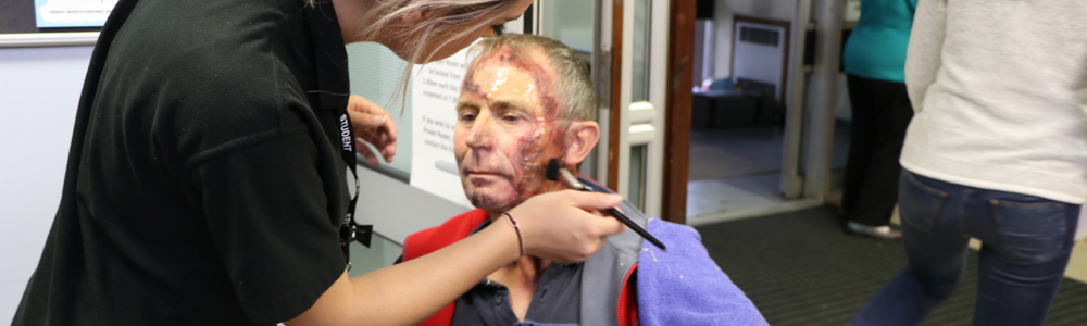 Beauty therapy student doing media makeup on the face of an adult male.