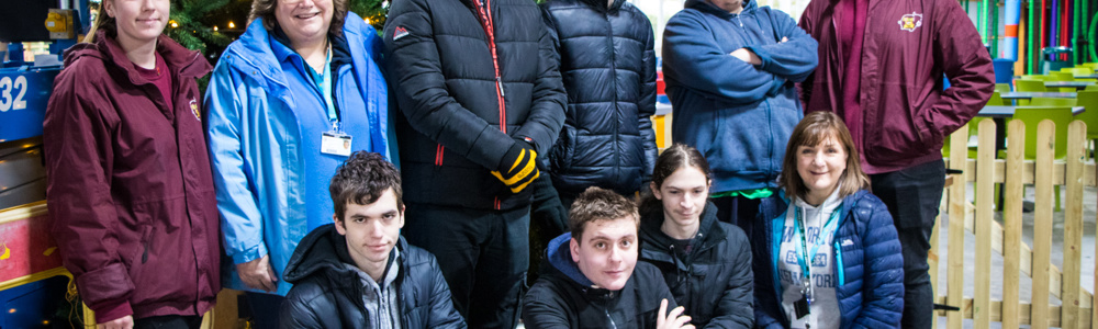 Group of students stood in front of a Christmas tree at a farm.