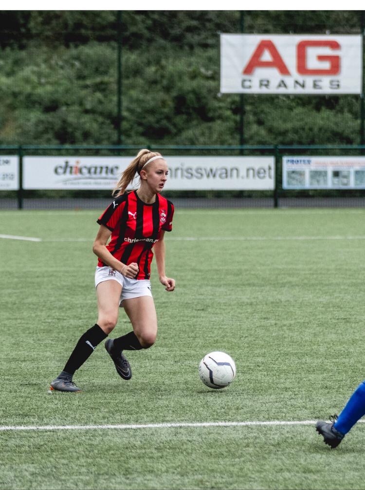Female playing football in red and black stripe jersey