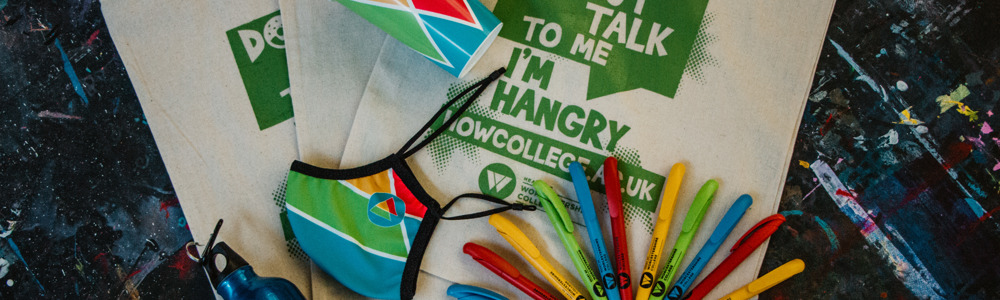 College of HoW College eco-friendly merch which includes Cotton canvas tote bag with the text Donut talk to me I'm Hangry, blue metal water bottle, green paper wristbands, HoW branded face covering, HoW branded reusable coffee cup and  red, green, blue and yellow pens