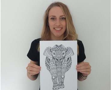 Collage for 2 images; left image of female smiling while holding a drawing of an elephant. Right image of fine drawing of an elephant with green plants and a pot of black pens.