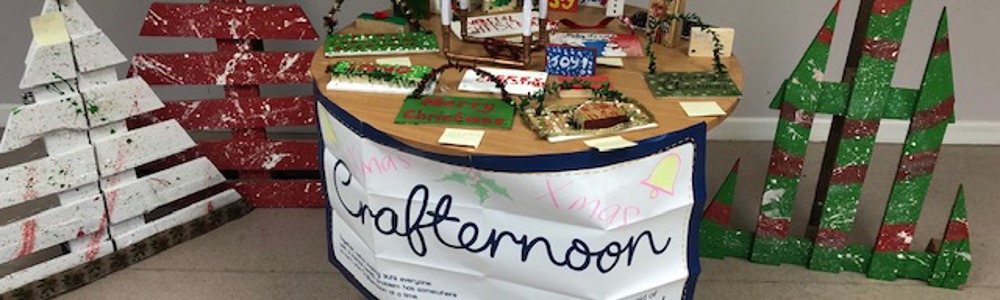 Craft table with 'Mind' charity logo, and Christmas trees made with palettes.