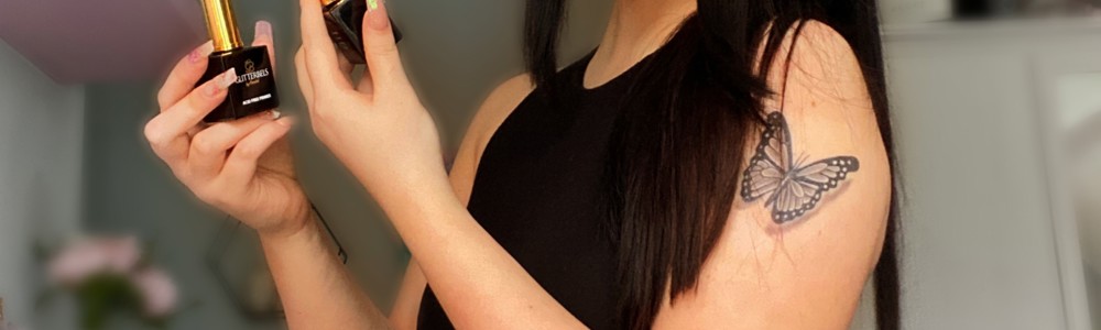 Female student standing in side profile holding two nail polish bottles