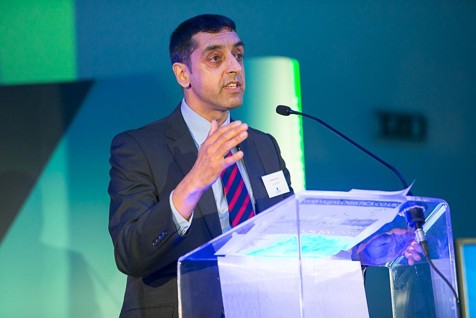 Male in a suit talking at a lectern