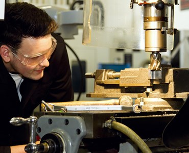 Male engineering student closely observing a machine and equipment