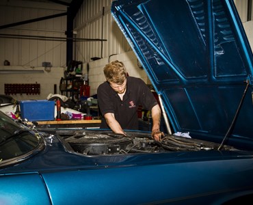 Male student working on the engine bay of a car
