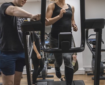female running on treadmill with gym partner stood next to her