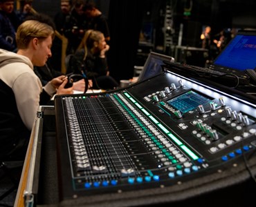 A close up of a music sound engineering equipment with students in the background