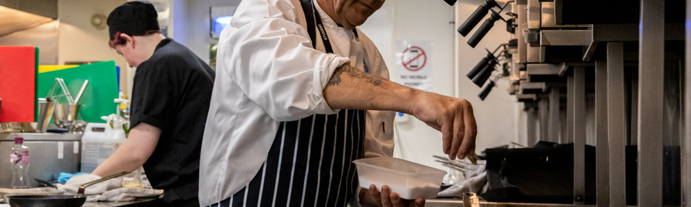 Budding apprentice chef, sprinkles salt into a hot pan