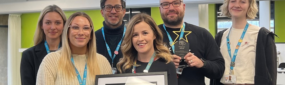 Picture of HoW Colleges marketing team smiling with their award in hand